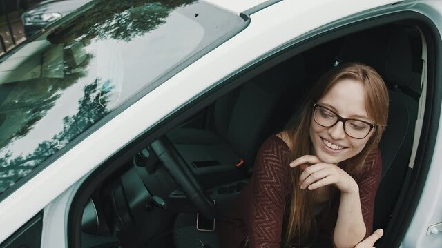 Happy face expression of young caucasian woman sitting on the driver seat of her new car. High quality 4k footage