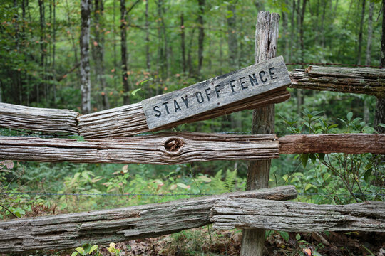 Stay off fence sign on a broken split rail fence