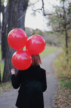 Girl walking on an autumn day with red balloons