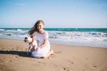 Happy girl with dog on sandy beach