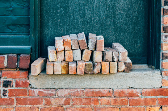 stack of red bricks against a green wall