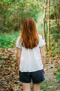 redheaded teen girl from behind in autumn woods