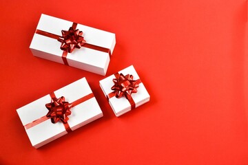 White gifts boxes with a red ribbon on a red background. Postcard for Valentine's Day or Mother's Day, Christmas and New year. copy space, flat lay. Holiday concept.