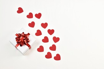 White gift box with a red ribbon with hearts on a white background. Postcard for Valentine's Day or Mother's Day, Christmas and New year. copy space, flat lay. Holiday concept.