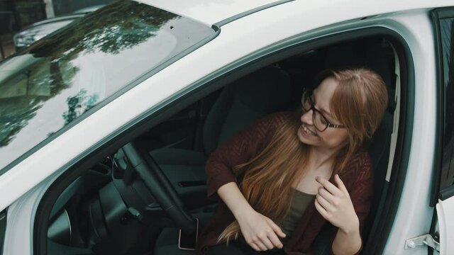 Happy face expression of young caucasian woman sitting on the driver seat of her new car. High quality 4k footage