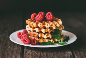 yummy belgian waffles with raspberries and mint leaves on wooden table