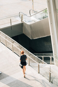 Ginger Woman Walking in a Modern Square in Milan . Italy