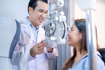 Asian woman and optometrist with optical phoropter during eye exam, diagnostic ophthalmology equipment, woman smiling and looking at optometrist, selective focus