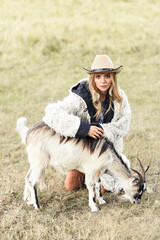 young beautiful girl in a hemp fur coat sits wit a goat