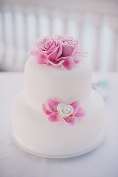 White fondant covered wedding cake with pink icing flowers