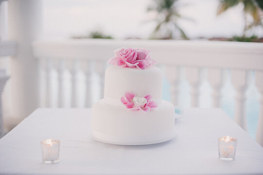 White fondant covered wedding cake with pink icing flowers