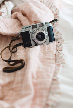 Old reflex camera and its leather strap on girl's unmade bed
