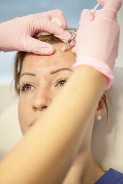 Woman recieving anti-aging injections in her forehead.