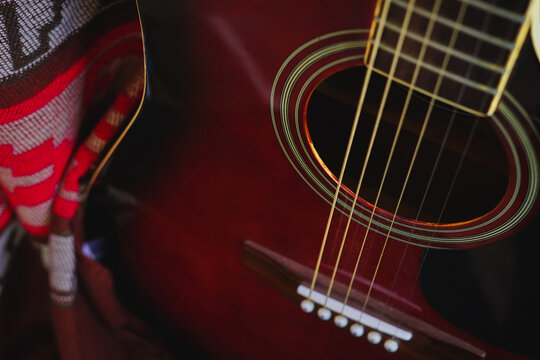 Close up of acoustic guitar in natural light with colourful gaucho poncho in the background. 