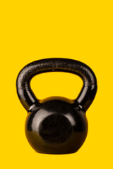 Naklejka na ściany i meble Black and heavy kettle bell isolated on warm yellow background