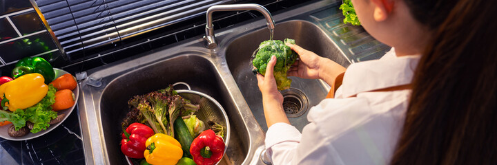 Woman hands washing Vegetables for Preparation of vegan salad on the worktop near to sink in a...