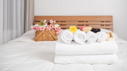 Fototapeta na wymiar Spa wellness concept with white towels,candle,milk soap,beautiful frangipani flowers in bamboo wooden basket on modern white bedroom