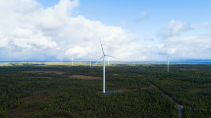 Wind mills power generators against autumn forest.
