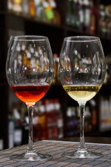 Glass of white and red wine on the background of shelving with bottles of wine