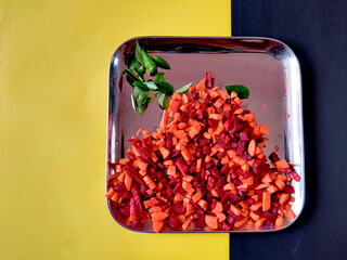 Raw carrots and beetroots in small pieces. Before cooking. Isolated on silver plate.Top view