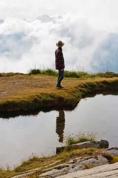 young man stands by water on mountain