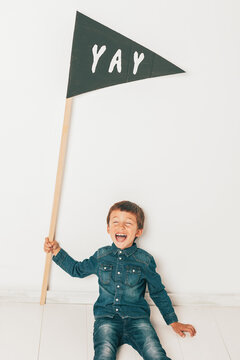 Little boy wearing denim clothes holding diy banner.