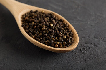 Black pepper peas on a wooden spoon on concrete table.