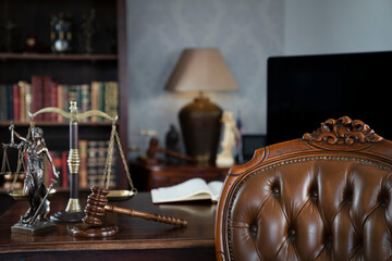 Law theme. Judge chamber. Themis, gavel and scale on brown shining desk. Collection of legal books in the bookshelf.