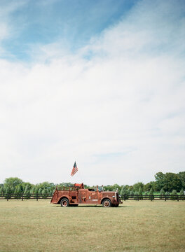 Old red and rusted fire truck with an American flag on a Christmas tree farm
