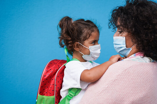 Mother Hugging Her Daughter Going Back To School While Wearing Surgical Face Masks - Main Focus On Girls Mask - Family Love And Health Care