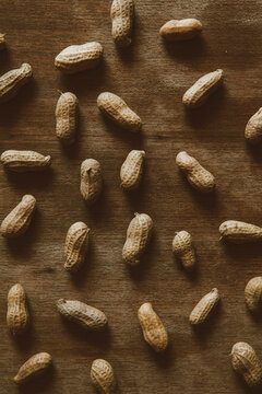 Background of raw peanuts scattered on a wooden table.
