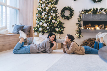 Positive young women relaxing on floor during Xmas holidays