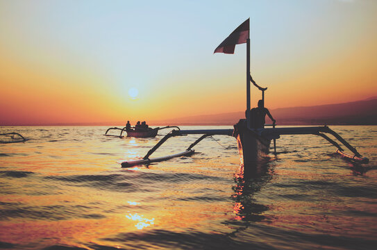 Silhouette of the traditional Indonesian wooden boats/catamarans sailing during the sunrise
