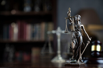 Law theme. Judge chamber. Themis, gavel and scale on brown shining desk. Collection of legal books...
