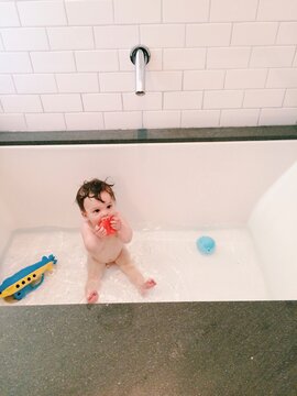 Baby taking a bath in a modern bathtub.