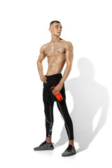 Fototapeta premium Resting. Beautiful young male athlete practicing on white studio background, portrait with shadows. Sportive fit model in works out in motion and action. Body building, healthy lifestyle, style