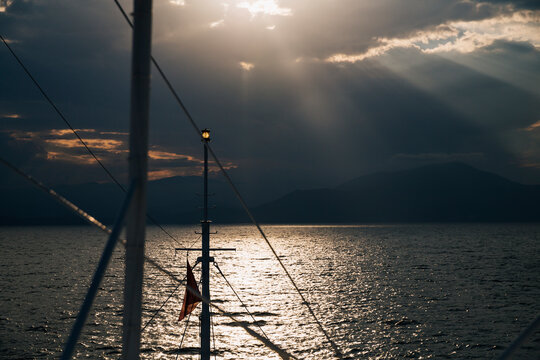 Sunset light penetrating from a grey sky seen from a sailboat