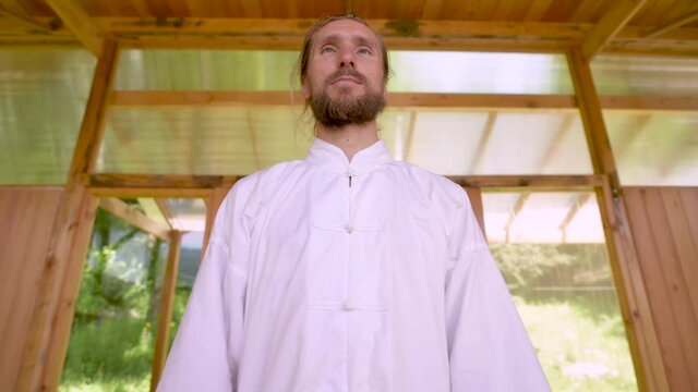 Close-up Bearded caucasian man wearing white clothes to practice concentration and breathing before practicing qigong tai chi