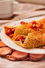 Gluten-free keto Crepes filled with pear, walnut and cinnamon in the oven with sea buckthorns on top. Autumn vegetarian breakfast or healthy dessert concept