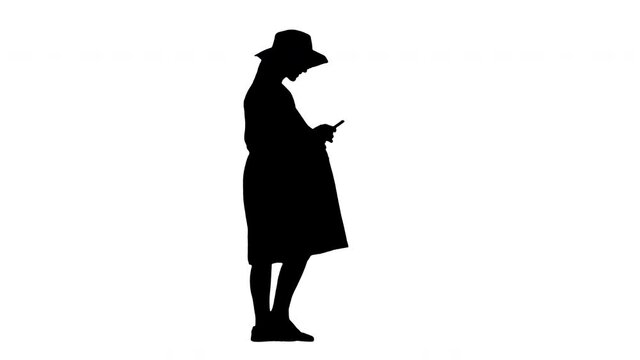 Young pregnant woman in trendy hat walking and using her phone, Alpha Channel