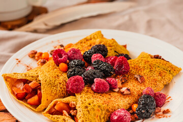 Gluten-free crepes stuffed with roasted pear, walnut and cinnamon, in the oven with fresh berries on top. Autumn comfort breakfast served on a natural linen background. Selective focus. Free space for
