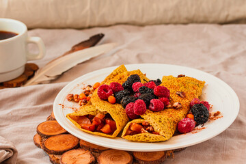 Gluten-free crepes stuffed with roasted pear, walnut and cinnamon, in the oven with fresh berries on top. Autumn comfort breakfast served on a natural linen background. Selective focus. Free space for