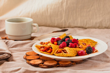 Gluten-free crepes stuffed with roasted pear, walnut and cinnamon, in the oven with fresh berries on top. Autumn comfort breakfast served on a natural linen background. Selective focus. Free space for