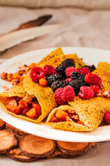Gluten-free crepes stuffed with roasted pear, walnut and cinnamon, in the oven with fresh berries on top. Autumn comfort breakfast served on a natural linen background. Selective focus. Free space for