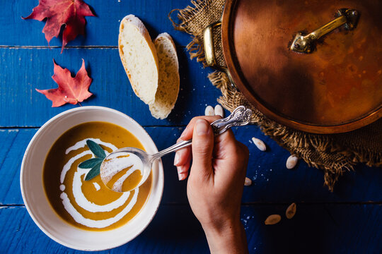 Woman's hand scooping butternut squash soup from a bowl