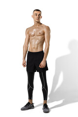 Fototapeta premium Posing. Stylish young male athlete practicing on white studio background, portrait with shadows. Sportive fit model in works out in motion and action. Body building, healthy lifestyle, style concept.