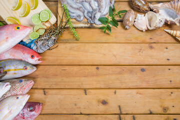 Seafood. Fresh tropical fishes, lobster, seashells and octopus on wooden table. Ingredients from...