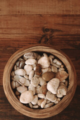 Close up decorative stones of different beige shades on a wooden plate on a blurred brown background. Top view. Vertical shot. Copy space