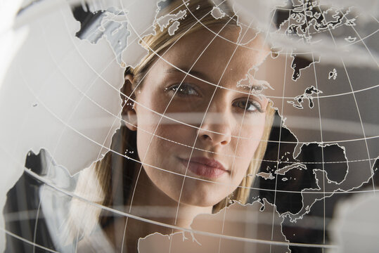 Studio portrait of woman peering through translucent world map