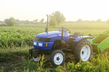 A farm blue tractor stands on the field. The use of machines in agriculture increases the speed and...